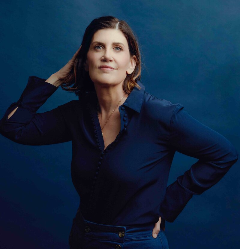 ✅ Alt Text: Professional branding portrait of Carolyn Vaughn, a West Des Moines photographer, posed against a deep blue background.

