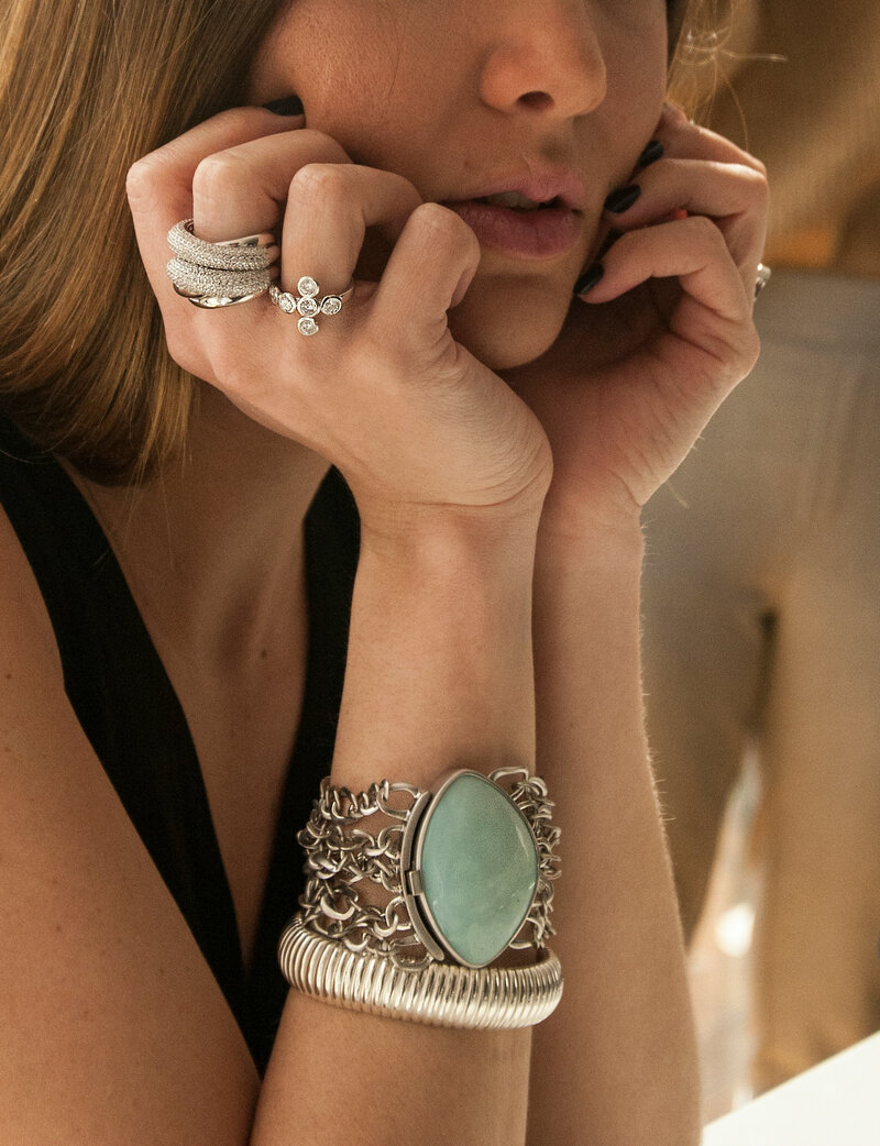 woman with rings and a bracelet with her chin in her hands