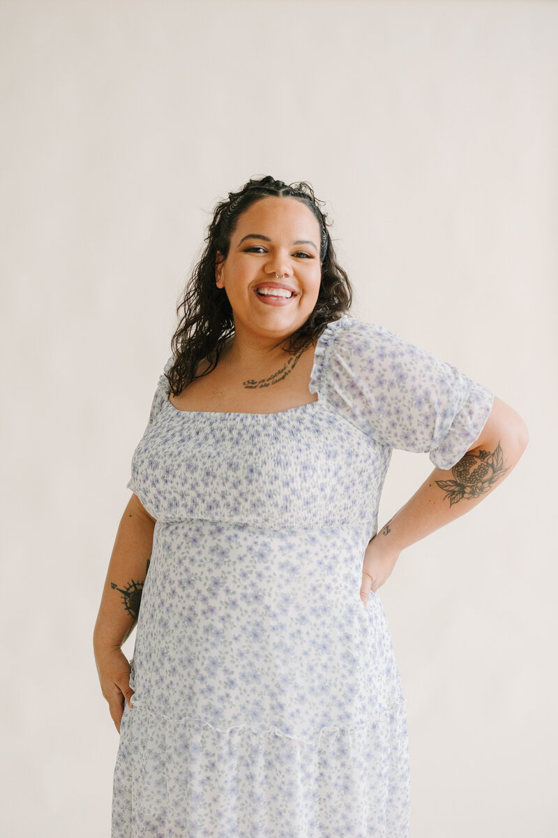 A person smiling with one hand on their hip