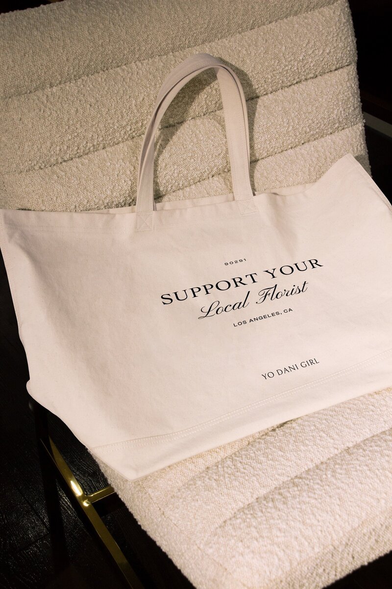 A beige custom made tote with black embroidery on a sherpa tan office chair