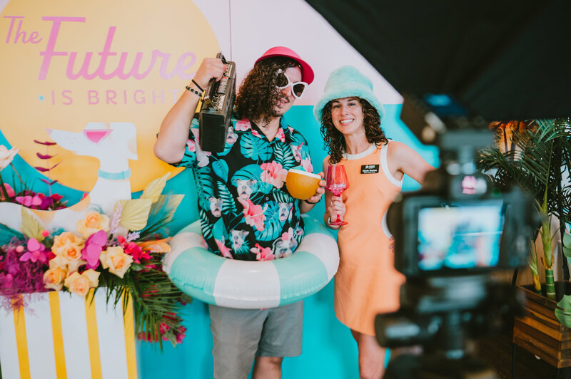 Two guests dressed in playful summer props pose at a branded corporate event in Phoenix, Arizona—captured by MISGIF’s professional event photography team during a colorful, themed brand activation.