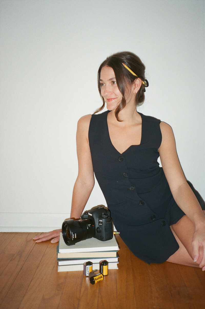 woman standing in tall grass holding a camera