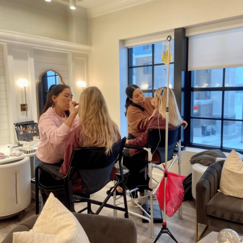Woman receiving IV therapy as they get their makeup done