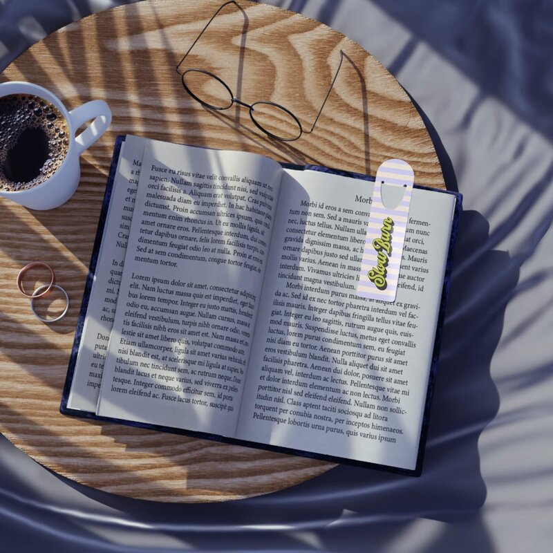 A cream and purple striped bookmark that says slow burn in a book.