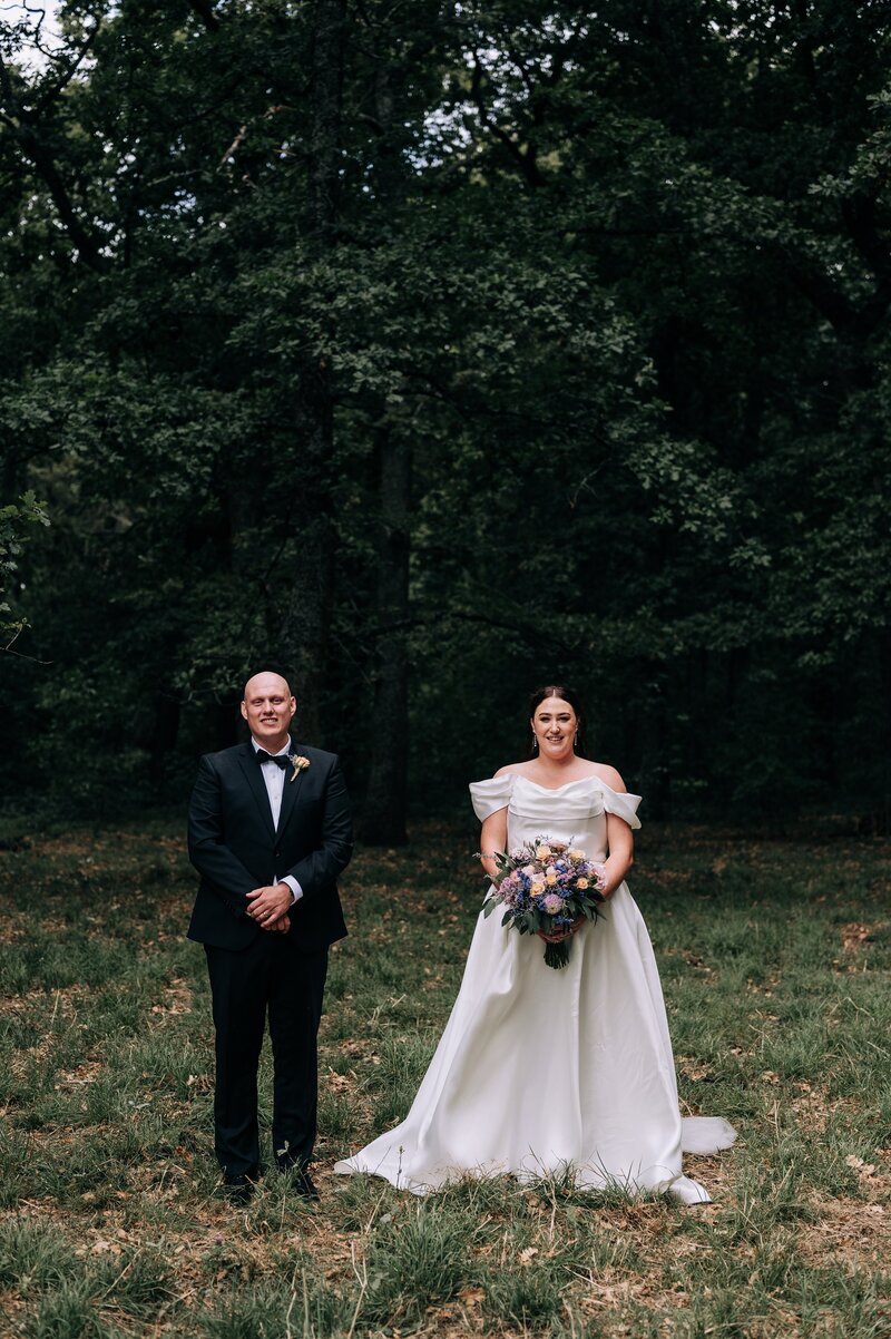 groom and bride stand side by side in forest at bangor farm in darfield