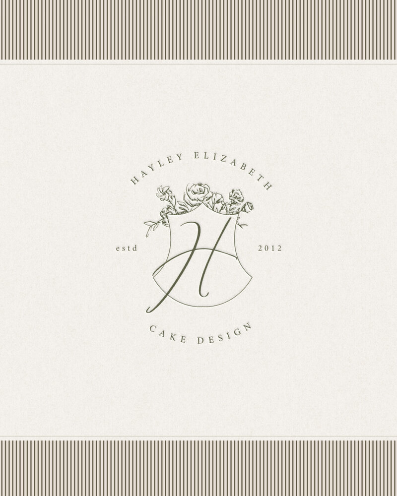 Elegant crest logo with floral detailing for Hayley Elizabeth, printed on cream textured paper