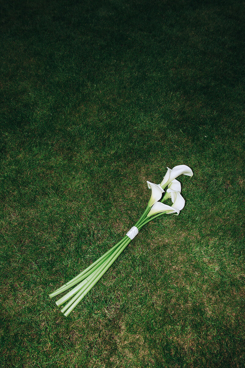 Luxurious bouquet of flowers on the green grass of Gonville & Caius in Cambridge at a wedding photographed using direct flash