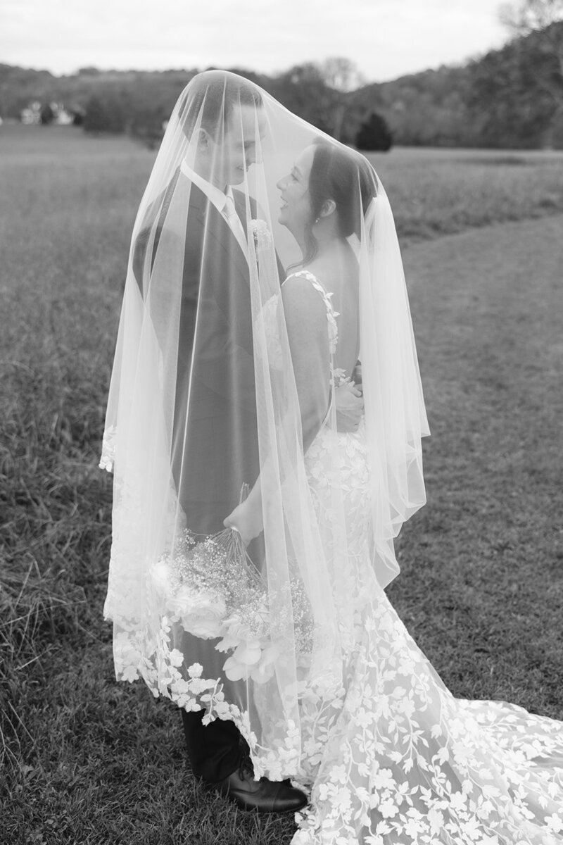 Black and white image of bride and groom under veil at Nashville wedding