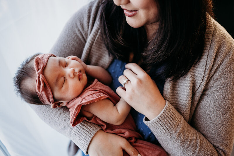 Newborn in moms arms with hand on cheek