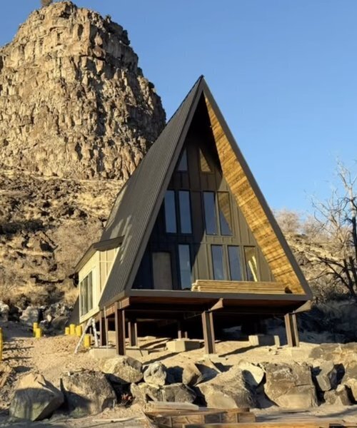 A-frame cabin under construction at The Perrine Hideaway, with exposed wooden beams and a rugged canyon backdrop