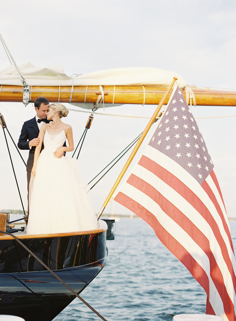 Bride and groom on sailboat with American flag at Chesapeake Bay Maritime Museum wedding