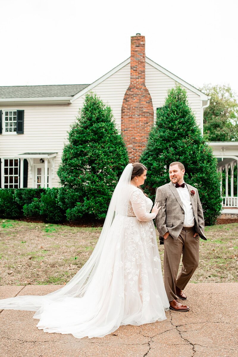 Groom turning to see his bride for the first time on their wedding day, historic home in the background