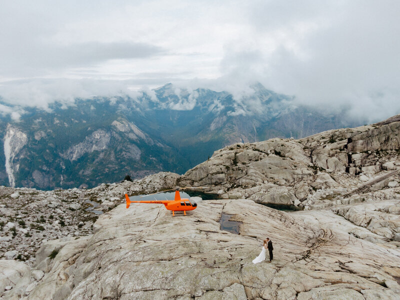A scenic mountain view of a helicopter parked on a rocky mountain top