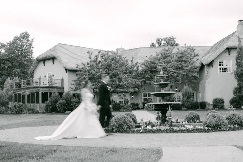 Bride and groom walking across lawn by one of the leading event planning companies minneapolis.