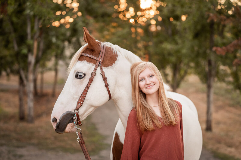 high school senior equestrian smiling with her paint horse