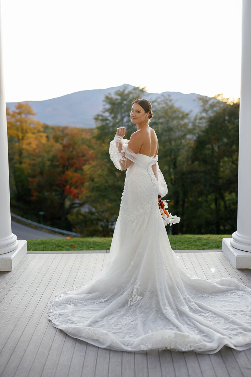Bride stands on front porch of North Carolina home looking out at mountains