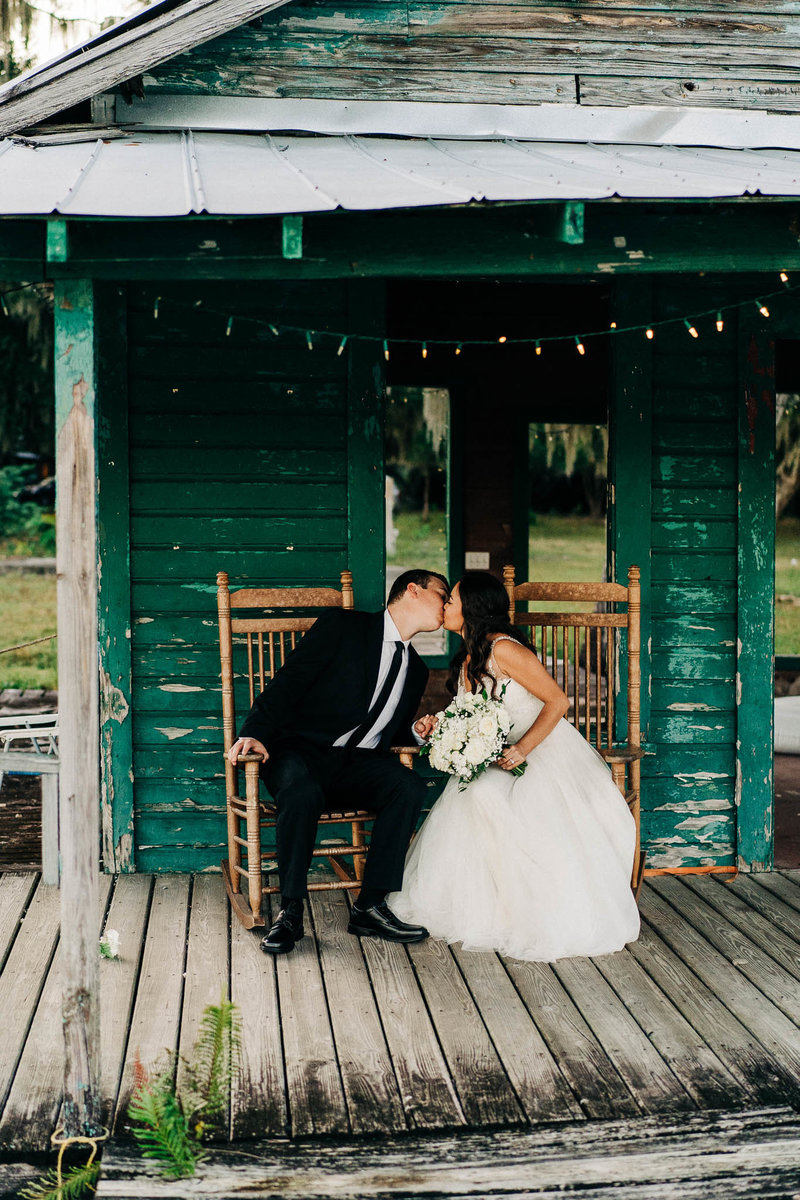 Newly married couple in front of the green boat house at barn at crescent Lake