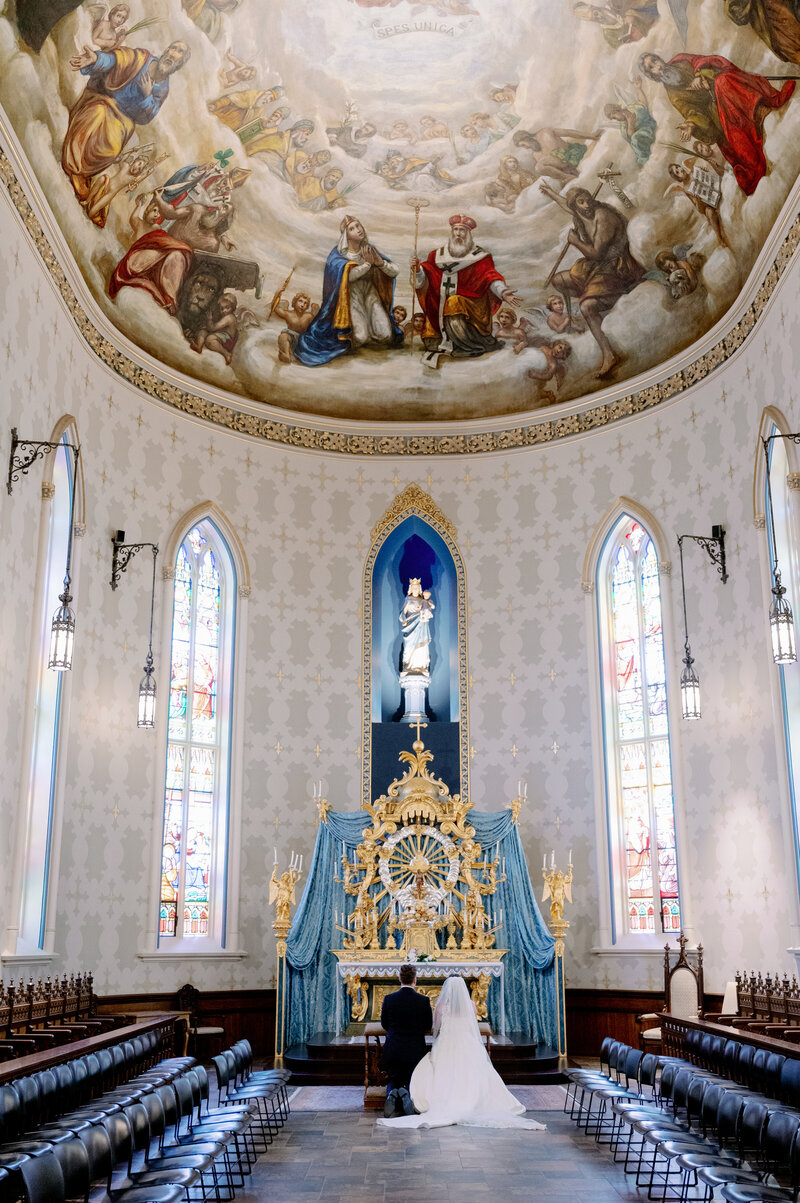bride and groom praying together in a Catholic church