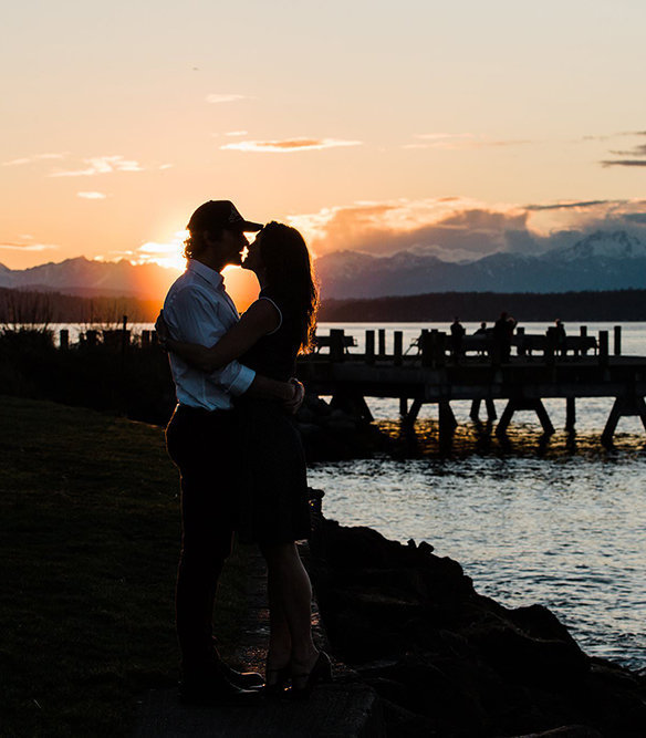A couples enjoys a stunning sunset on the beach in West Seattle during their engagement session with Seattle elopement photographer Amy Galbraith