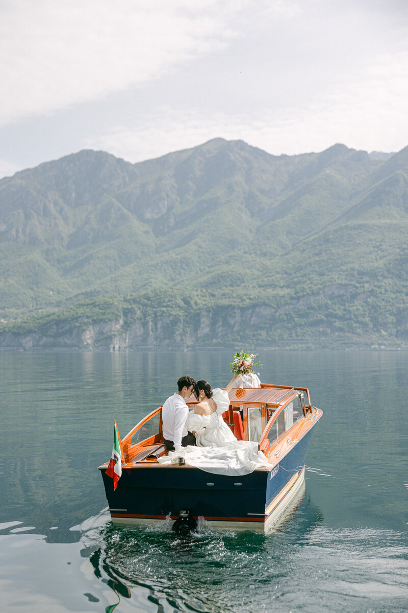 newlyweds riding in a boat on a lake in Italy