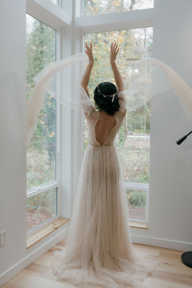 Bride twirling near large windows, veil flowing in the air