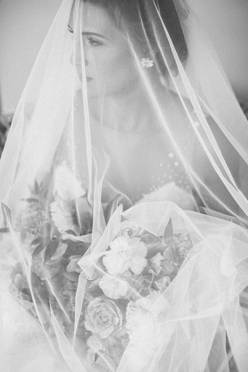 Black and white photo of a bride's veil draped over her bouquet