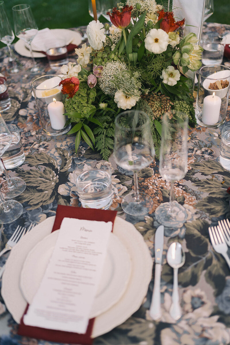 Place setting with a burgundy menu and garden florals on a patterned linen