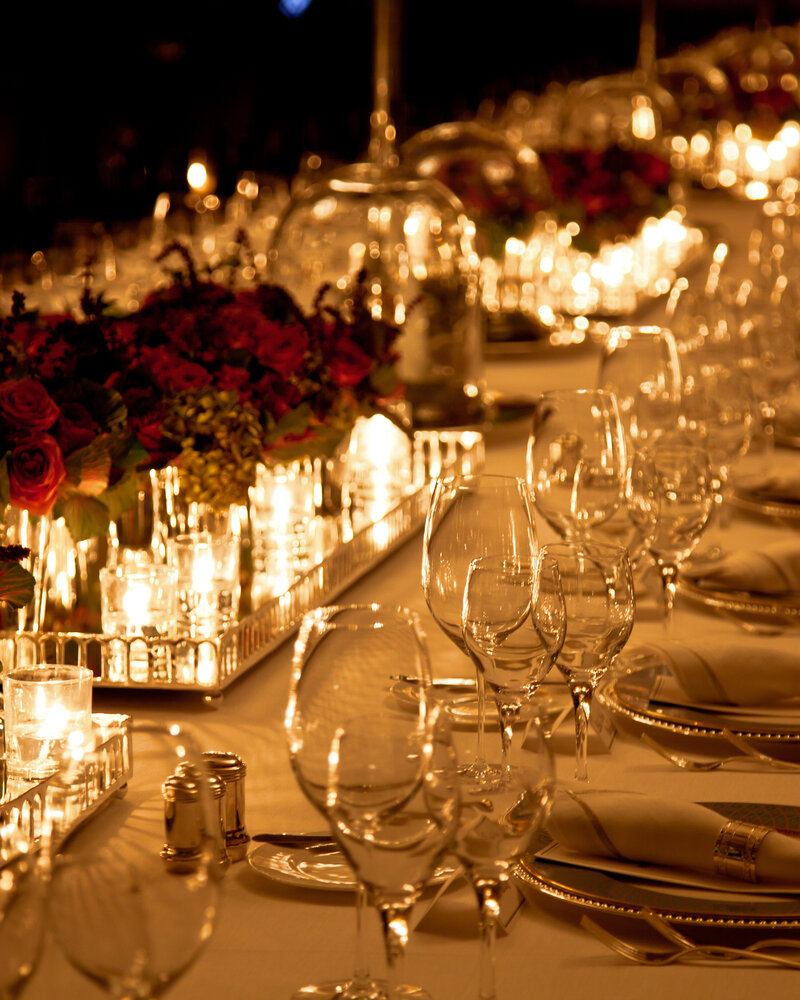 Elegant candlelight dinner table setting with red roses at a party.