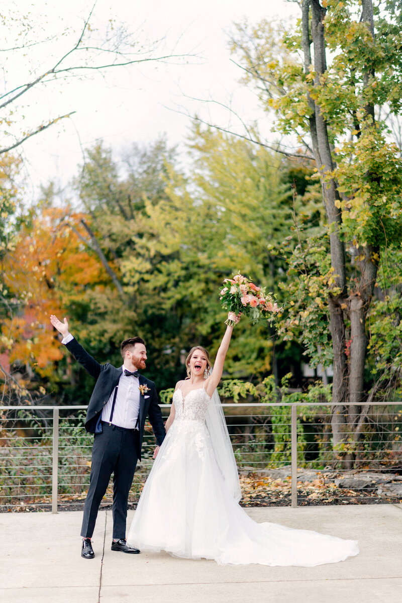 joyful bride and groom throw hands in the air to celebrate