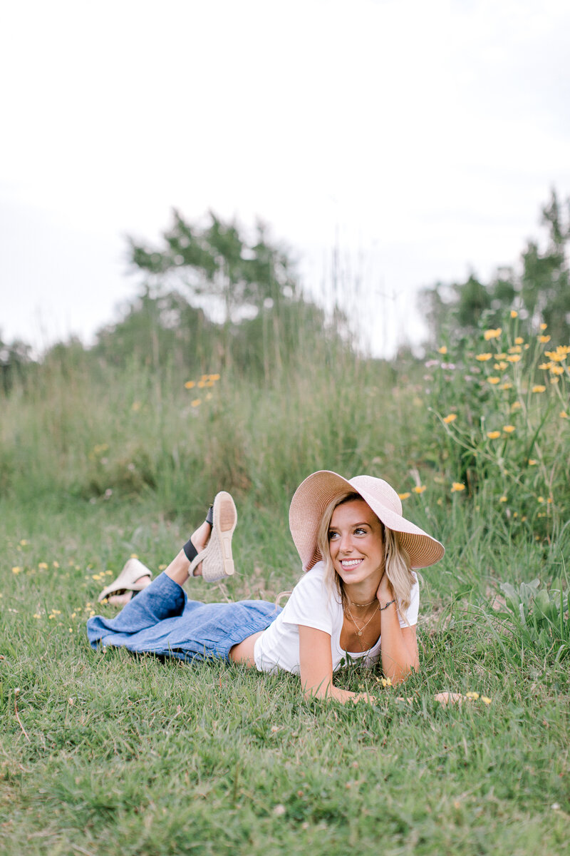 senior girl lying on grass looking and smiling off camera