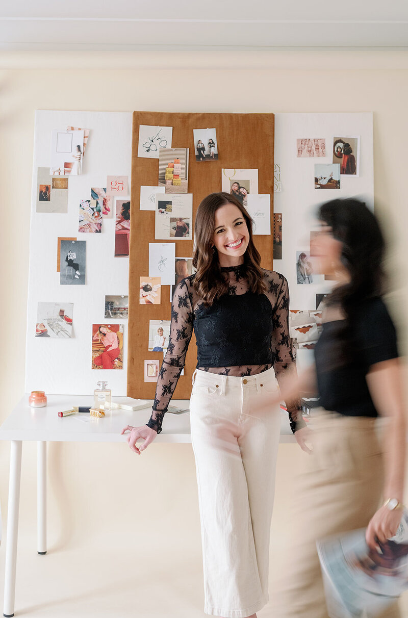 Brand designer Kelsea Buddo stands in front of inspiration boards on a table