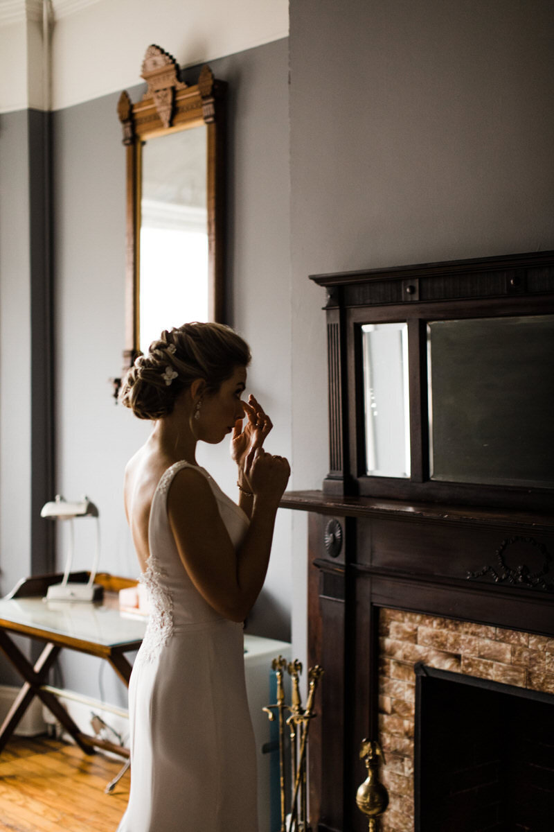 Profile shot of elegant bride touching up her makeup in mirror