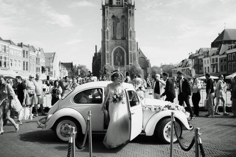 Bruidegom stapt uit auto voor de kerk in Delft, vastgelegd door trouwfotograaf Julia de Groot