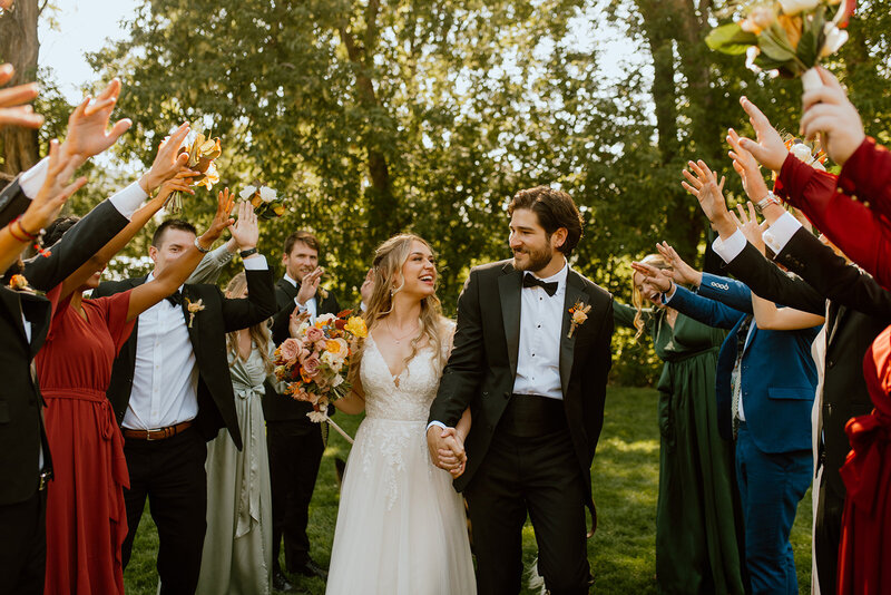 husband and wife walk with wedding party