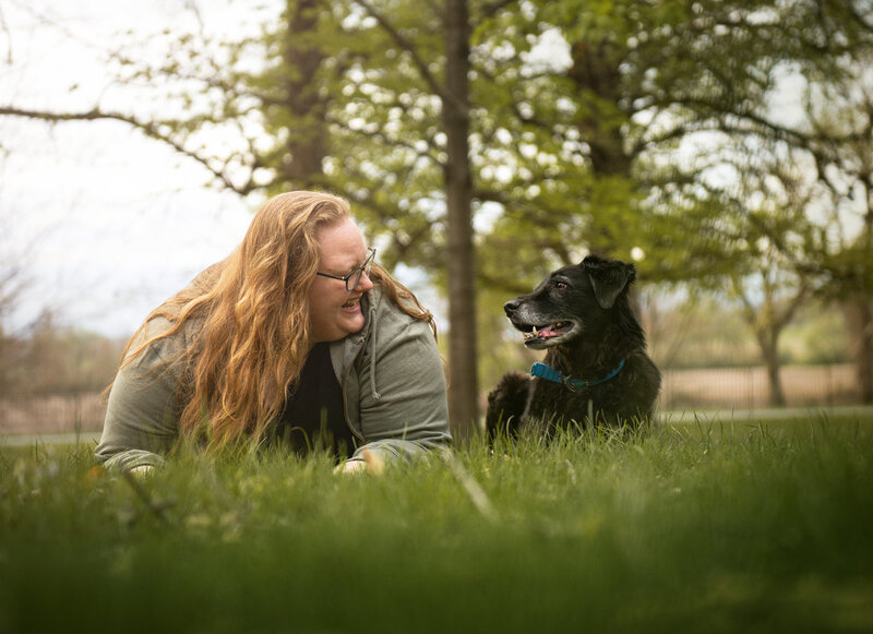 A older black dog and owner are laying on the ground during a photoshoot. 
Work by Duluth-based pet photographer Joanna of Paddle Paws Photography.