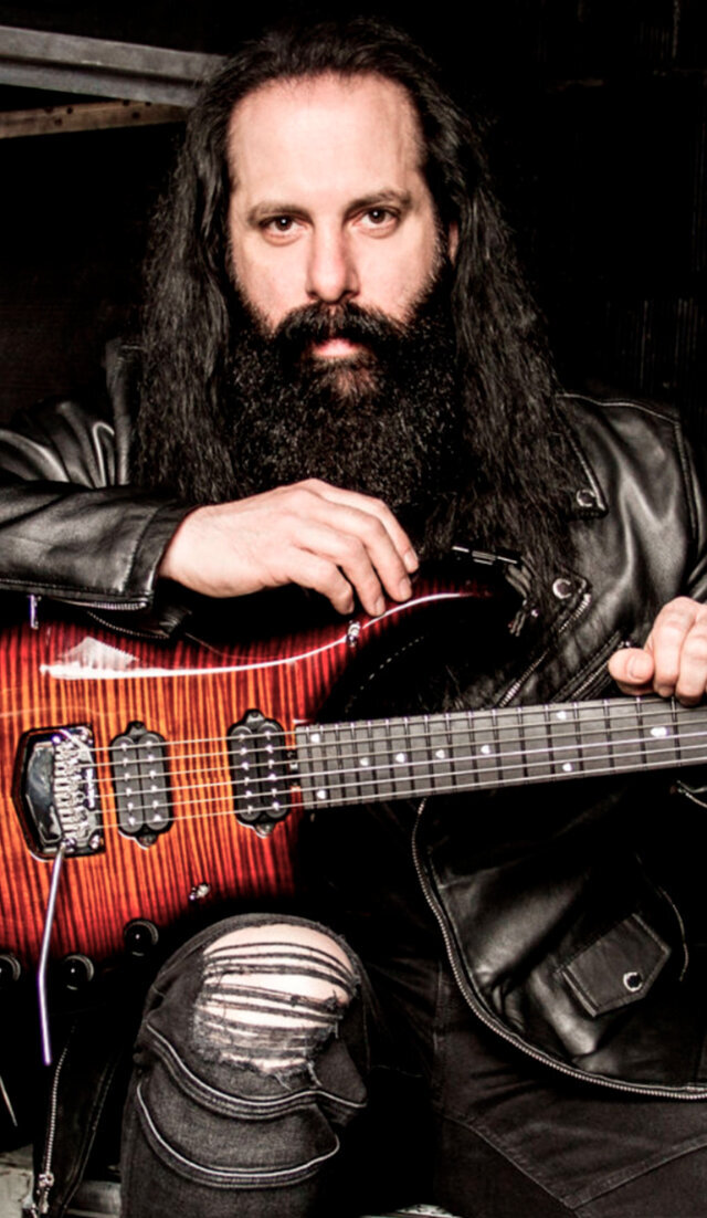 Music  portrait John Petrucci sitting with red guitar wearing leather jacket