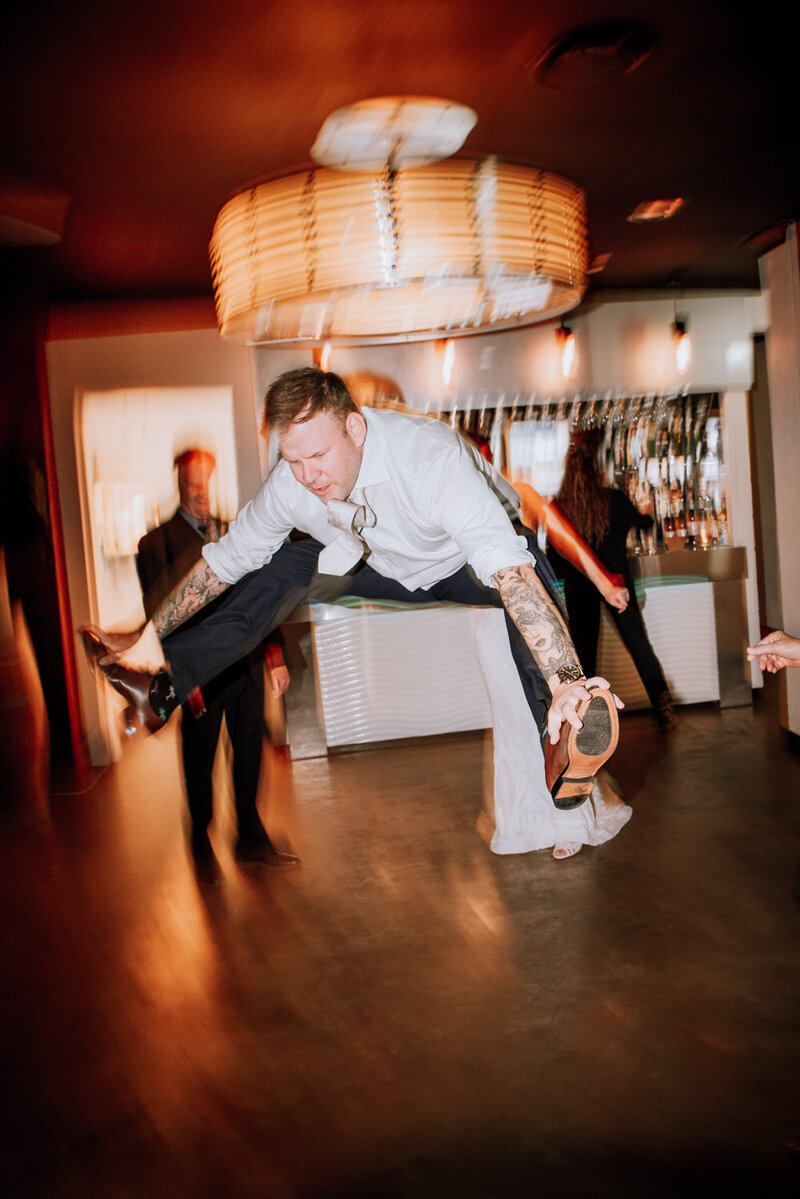 Groom doing the splits in the air on a dancefloor
