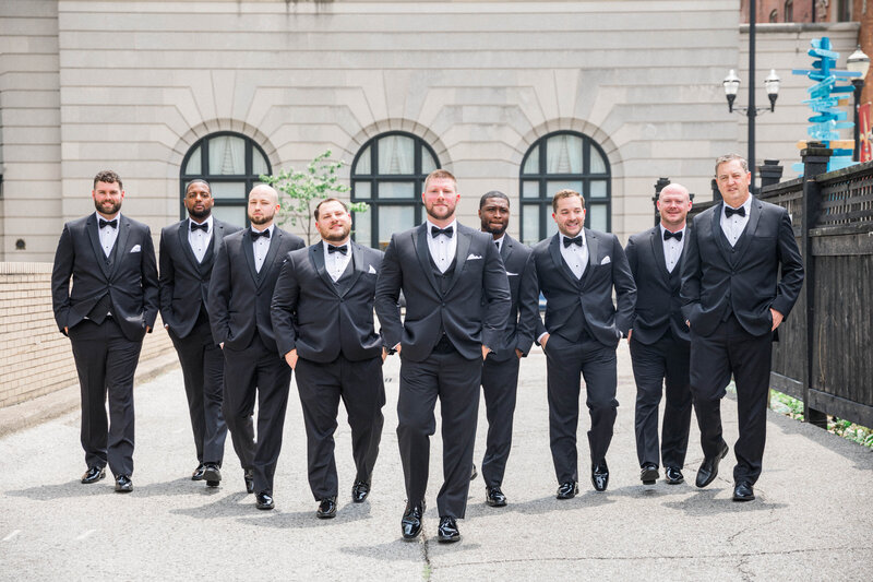 portrait of groomsmen walking on street