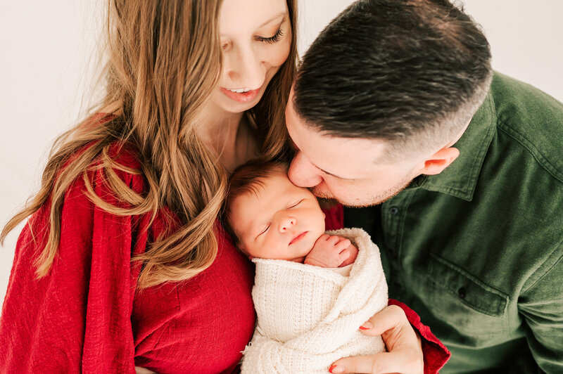 dad kissinb newborn baby on cheek in Springfield MO newborn photogrpahy studio