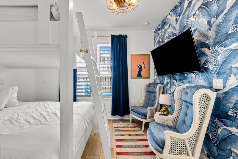 Playful and stylish bunk room with large TV, peacock artwork, and tropical wallpaper—great for group getaways or content creators near Santa Rosa Beach.
