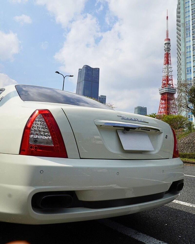 Rear view of the white Maserati Quattroporte with Tokyo Tower in the background, captured during a luxury city driving tour with Tokyo Luxe Drive.