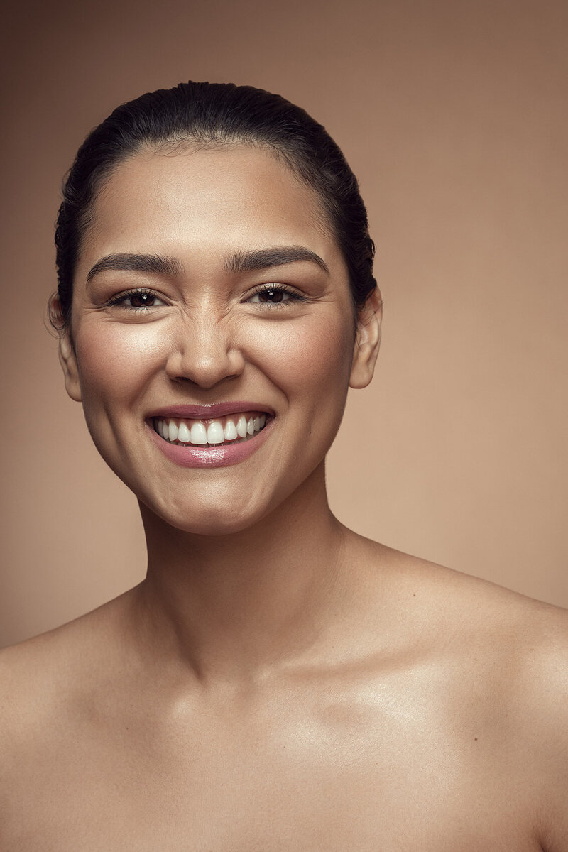 Karina Perez in a radiant studio portrait, highlighting her bright smile and natural glow, shot by Ylva Erevall.