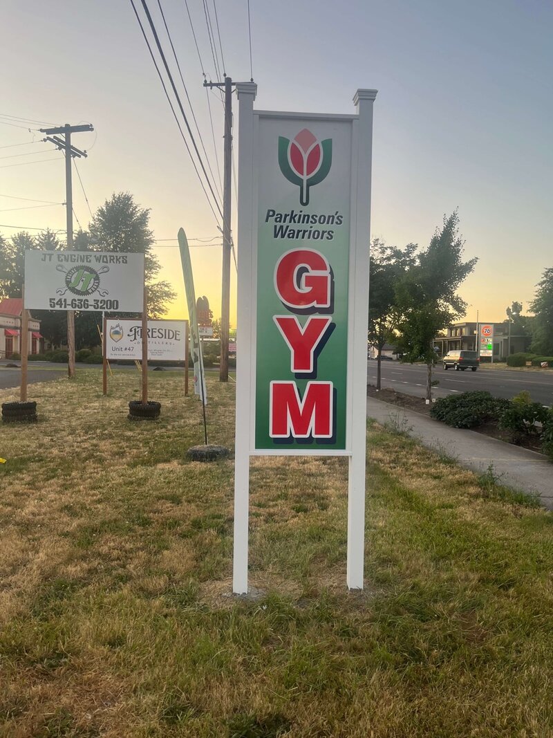 Sign on the side of the street marking where to find the Parkinson's Warriors Gym