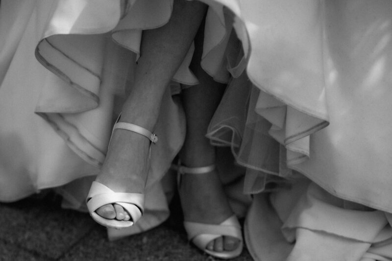 Eine Nahaufnahme der Füße der Braut in ihren Schuhen, als sie sitzt.