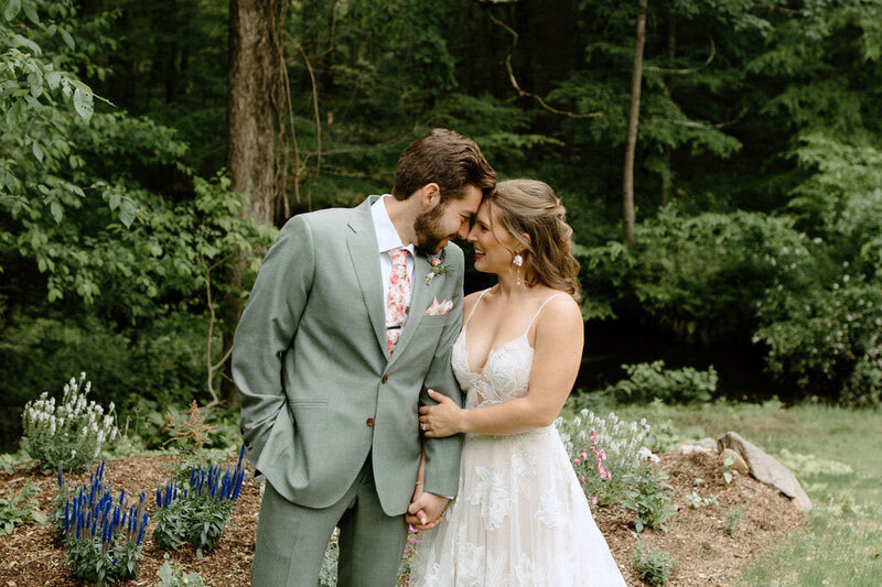 Bride and groom holding each other with greenery background