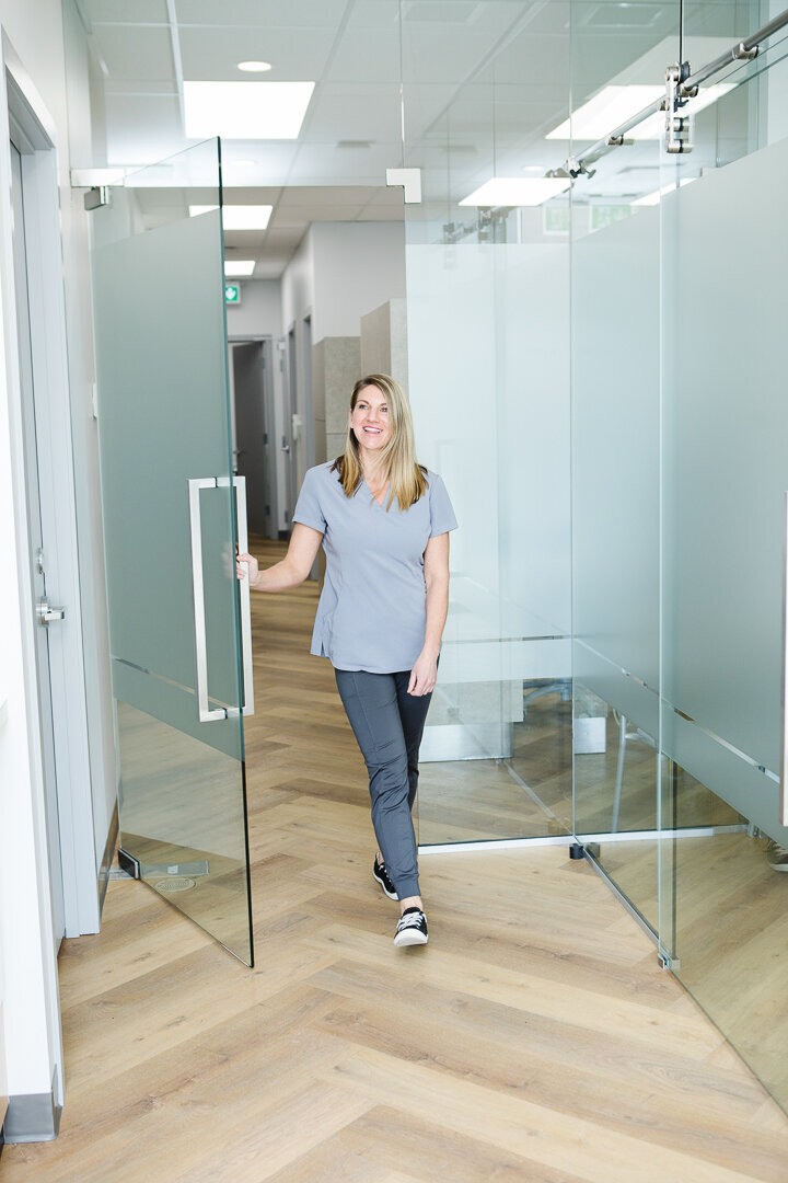 A woman smiling while holding the door