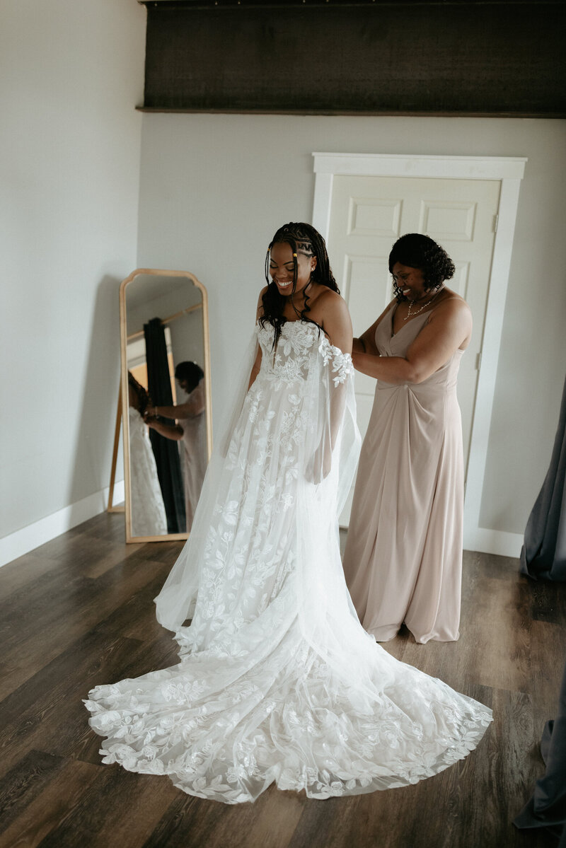 Mother helping her daughter put on a dress.