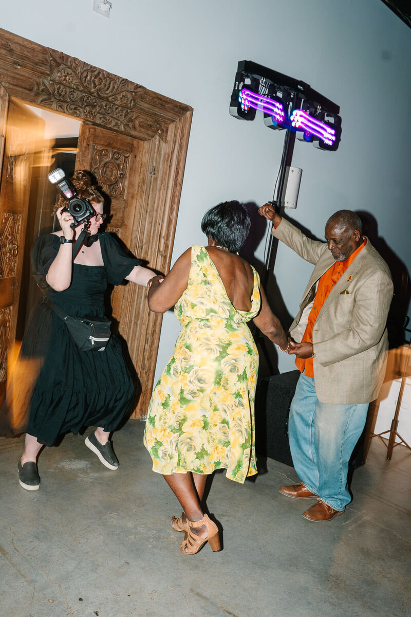 Flash photo of Allison Bolin Texas wedding photographer dancing with guests at wedding reception