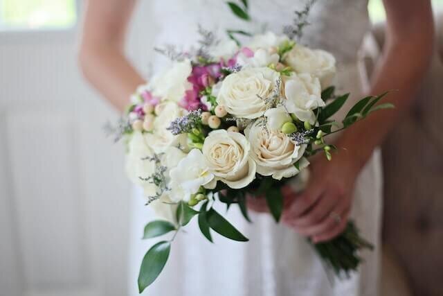 Bride hands holding wedding bouquet of white, pink and purple flowers