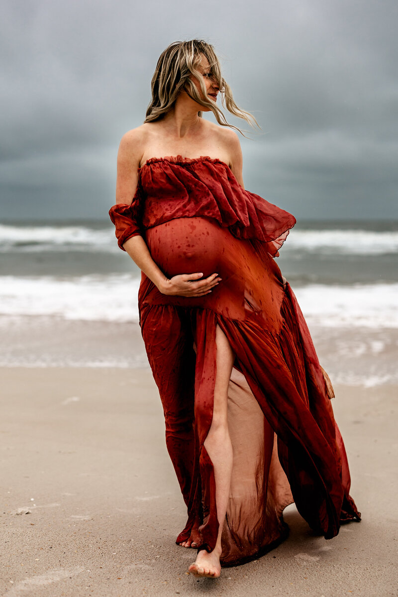 Pregnant woman walking towards the camera on the beach